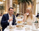 Couple enjoying afternoon tea at a elegant restaurant, with a three-tiered pastry stand in front of them and champagne flutes on the table.