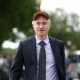 Palantir CEO Alex Karp walking outdoors wearing a cap