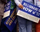 People holding "Billionaire Tax Now" campaign signs