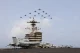 Fighter jets flying in formation over a US aircraft carrier