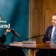 Daron Acemoglu being interviewed at a table for Bloomberg Weekend
