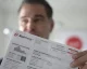 Man holding up an Xcel Energy utility bill